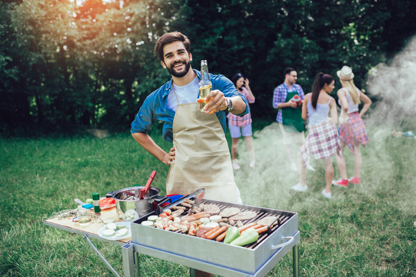 Bonito macho preparando churrasco ao ar livre para amigos
 - Foto, Imagem