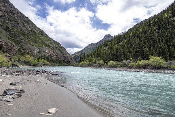 rivière de montagne avec de l'eau turquoise avec un banc de sable de galets gris et des pierres de différentes tailles
 - Photo, image
