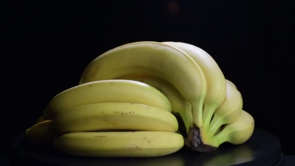 Manojos de plátanos girando fruta sobre fondo negro
 - Metraje, vídeo
