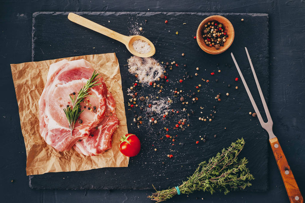 Uncooked raw pork chops with spices and bbq fork on a table .  - Photo, Image