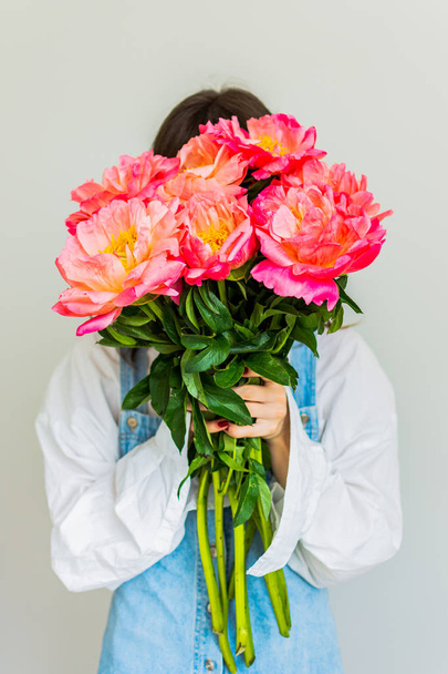 Girl covers her face with a beautiful bouquet of peonies - Photo, Image