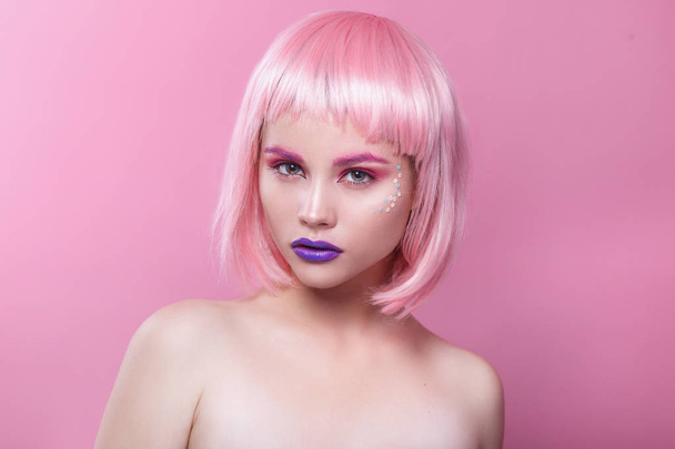 attractive young woman with pink bob cut and purple lips looking at camera isolated on pink background - Zdjęcie, obraz