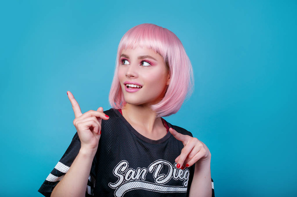 Pop girl portrait wearing pink wig looking showing the way - Fotó, kép