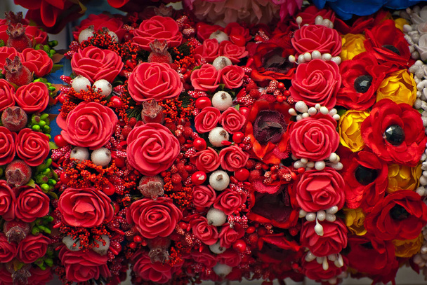 Panayırda yapay çiçek buketleri satılıyor. Renkli küçük çiçeklerden yapılmış korolalar. Ulusal dekorasyon ve giysi aksesuarlarının kapatılması. - Fotoğraf, Görsel