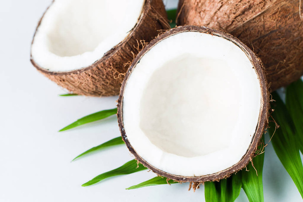 Зрізати половину кокосового горіха з зеленим листям на білому тлі. Ізольована концепція
.  - Фото, зображення