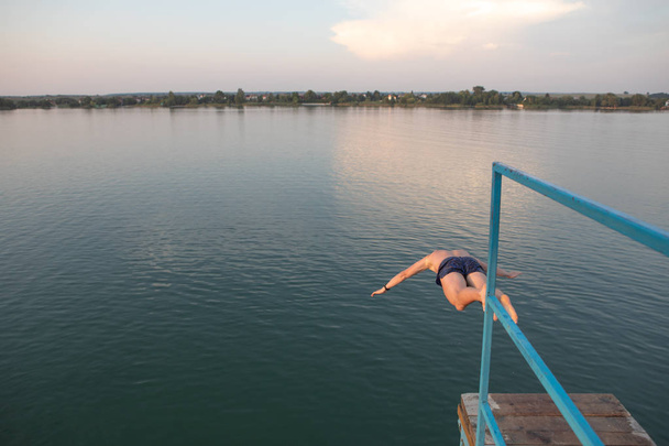 homme sautant de la tour à l'eau du lac au coucher du soleil
 - Photo, image
