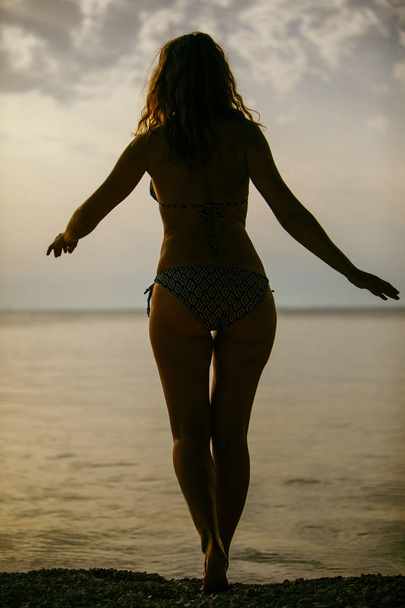 Nainen uimapuvussa meren edessä ei kasvoja
 - Valokuva, kuva