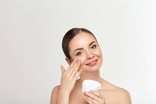 beautiful model applying cosmetic cream treatment on her face on white background - Фото, зображення