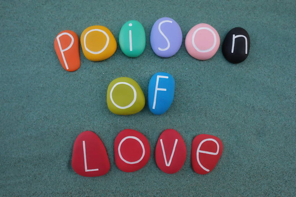 Poison d'amour, texte créatif composé de pierres multicolores sur sable vert
 - Photo, image