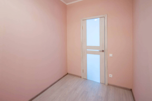 白塗りのフローティングラミネートフローリングと背景に新しく塗装されたピンクの壁を持つ空の小さな部屋 - 写真・画像