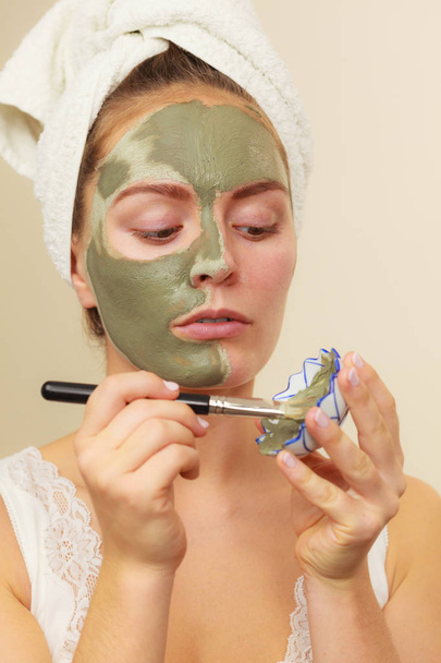 Woman applying with brush clay mud mask to her face  - Фото, изображение