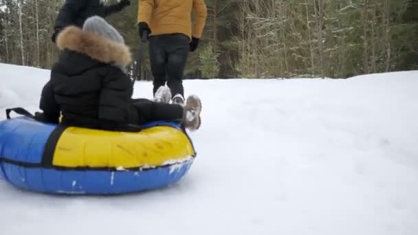 Happy parents are running and sliding their son in tubing in winter park. - Footage, Video