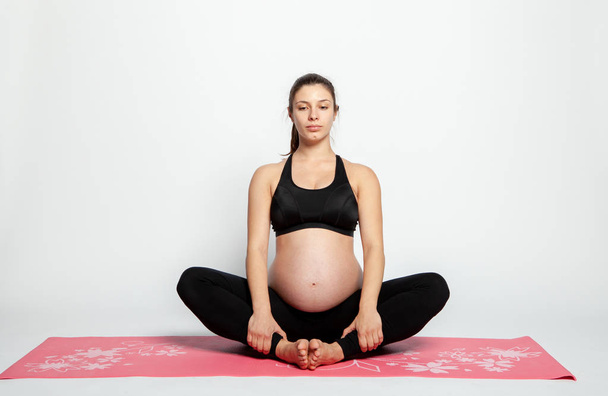 Young pregnant woman doing gymnastics. - Fotografie, Obrázek