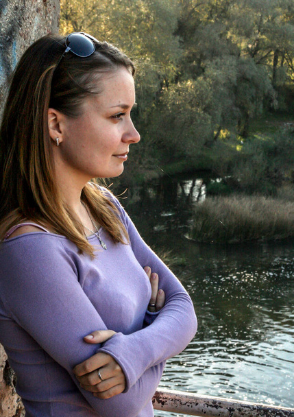2010.10.10, Obninsk, Russia. Long hair woman standing by the wall on background of the river, side view. Portrait of a beautiful woman. - Photo, image