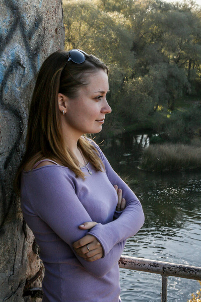 2010.10.10, Obninsk, Russia. Long hair woman standing by the wall on background of the river, side view. Portrait of a beautiful woman. - Foto, Bild