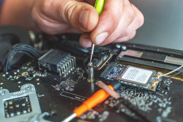 a man repairs a computer, solders a board, repairs electronics a - Photo, Image