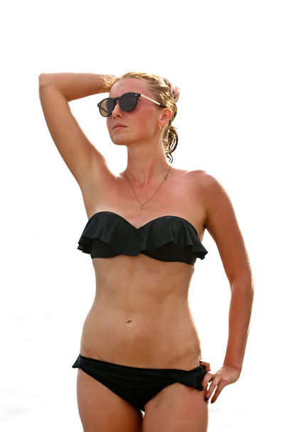 Woman in sunglasses and black swimsuit on white background - Foto, Imagen