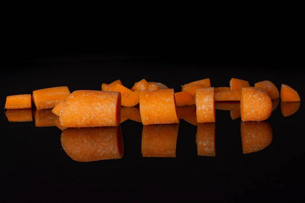Orange baby carrot isolated on black glass - 写真・画像