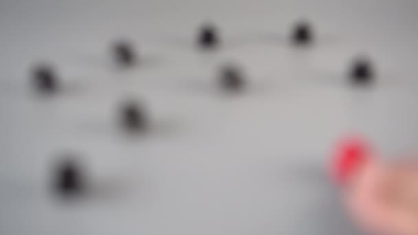 Uma mão define uma figura vermelha cercada por figuras pretas em uma superfície cinza. Conceito de Líder de Equipe
 - Filmagem, Vídeo
