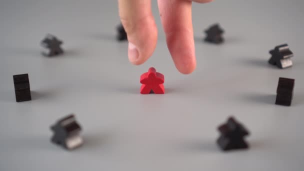 The hand removes the red figure from the environment of black figures on a gray surface. The concept of the dismissal of the leader from the team - Video, Çekim