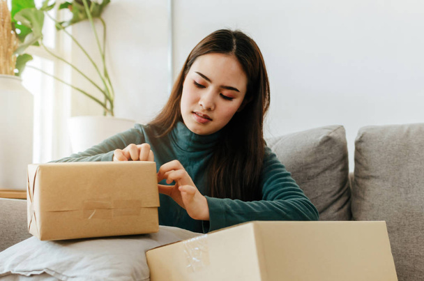 SME startup. asian young entrepreneur woman working and packing cardboard parcel box for send order to customer at home office, shopping online, small business owner, logistics and delivery concept - Foto, afbeelding