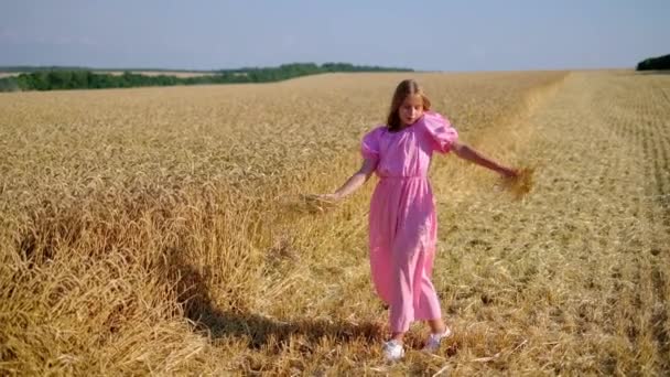 Τρυφερό έφηβο κορίτσι που πετάει σιτάρι στο χωράφι και χορεύει σε όμορφο αγροτικό μέρος - Πλάνα, βίντεο