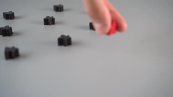 Une main met une figure rouge entourée de figures noires sur une surface grise. Concept de chef d'équipe
 - Séquence, vidéo