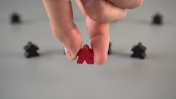 Ręka ustawia czerwoną figurę otoczoną czarnymi postaciami na szarej powierzchni. Koncepcja lidera zespołu - Materiał filmowy, wideo