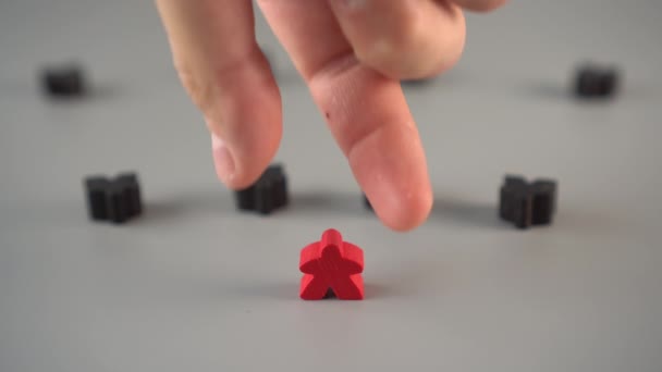Ręka usuwa czerwoną figurę z otoczenia czarnych figur na szarej powierzchni. Koncepcja zwolnienia lidera z zespołu - Materiał filmowy, wideo