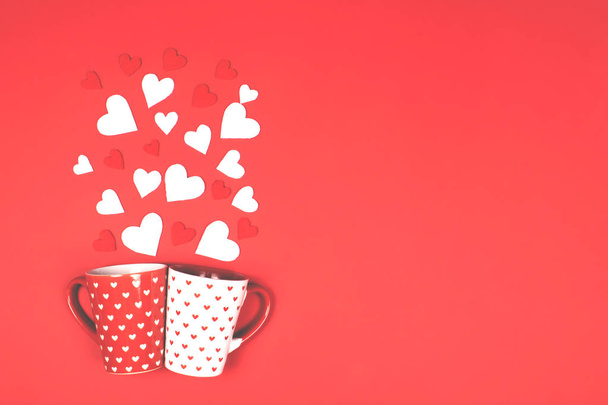 Two mugs with scattered hearts on red. - 写真・画像