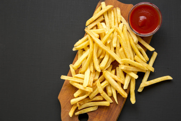 French fries with sauce on a black surface, overhead view. Copy  - Fotó, kép
