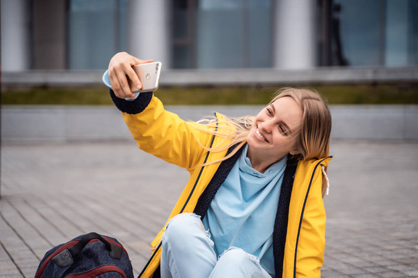 Όμορφο κορίτσι παίρνει selfie στο smartphone και κάθεται στο σκέιτμπορντ. - Φωτογραφία, εικόνα