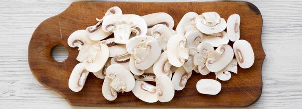 Chopped mushrooms on a rustic wooden chopping board on a white w - Photo, Image