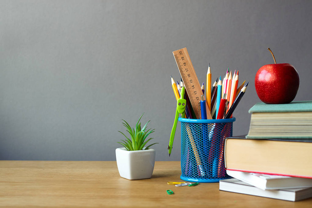 Concept de retour à l'école, fournitures scolaires, pile de livres, pomme rouge et succulente dans un pot blanc sur une surface en bois, mise au point sélective
 - Photo, image