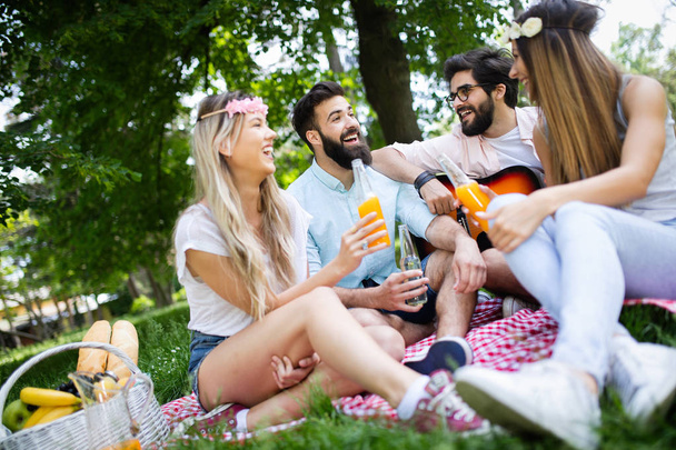 Summer, vacation, music and recreation time concept. Cheerful friends have picnic outdoor. - Foto, imagen
