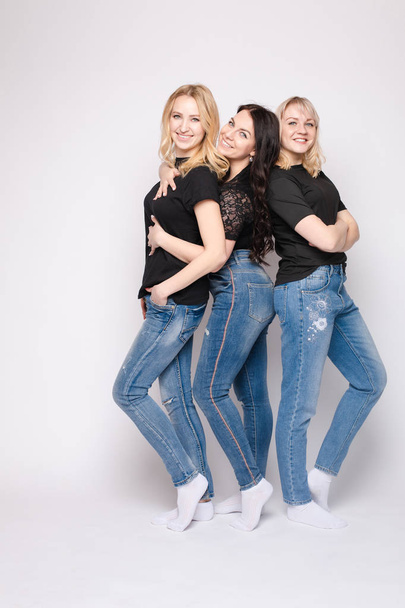 Groep van lachende jonge vriend vrouw knuffelen poseren kijken naar camera op witte studio achtergrond - Foto, afbeelding