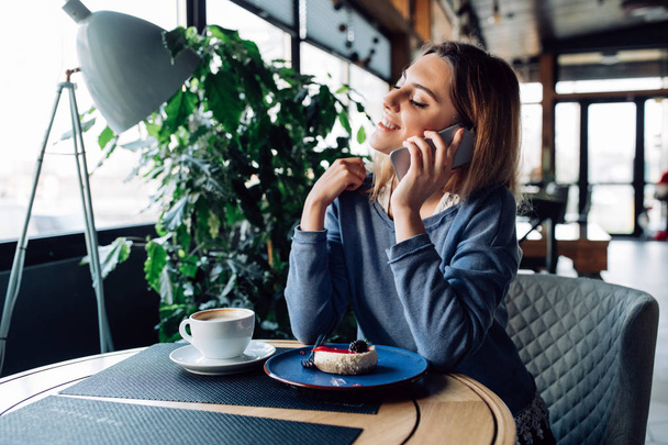 Hermosa chica hablando por teléfono mientras descansa en el café
 - Foto, Imagen