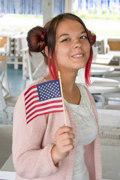 Menina adolescente sorrindo e segurando bandeira americana, feriado nacional, plano médio
 - Foto, Imagem