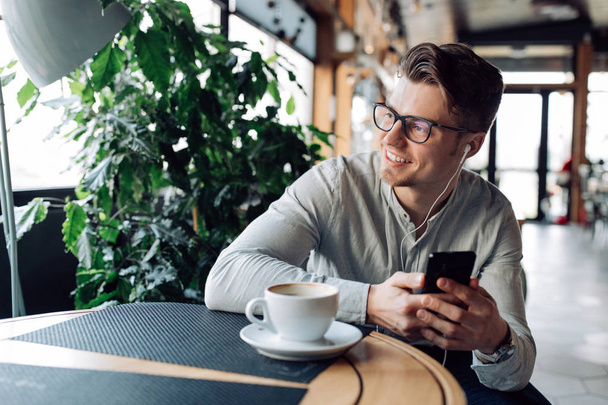 Smiling guy listening to music in headset, spending time at cafe - Foto, Bild