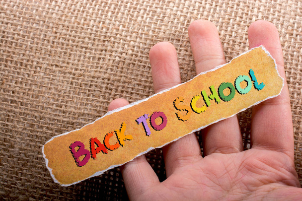 Voltar para a escola escrito em papel amarelo rasgado na mão
 - Foto, Imagem