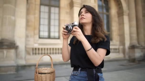 PARIS, Pretty woman making photo with a film camera on background. Old buildings in Paris on background - Záběry, video