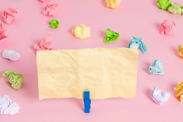 Colored crumpled sheets placed around the empty rectangle square shaped reminder note in the pink background. Office supplies, blank paper pinned by a fastener. - Photo, Image