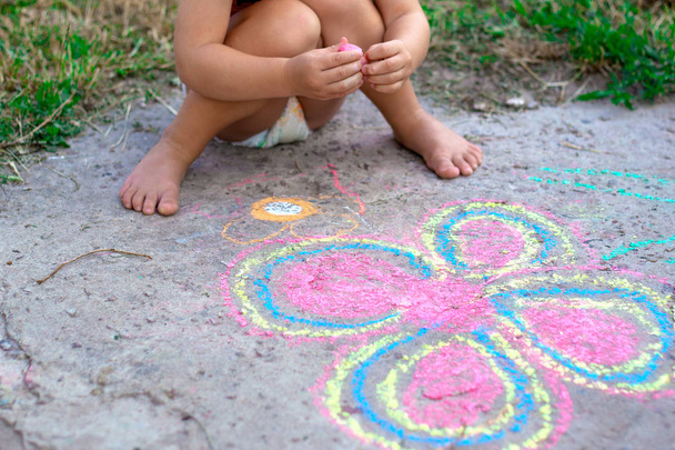 κοριτσάκι ζωγράφισε ένα λουλούδι στο πεζοδρόμιο, το παιδί ζωγραφίζει ένα λουλούδι στο δρόμο με κιμωλία - Φωτογραφία, εικόνα