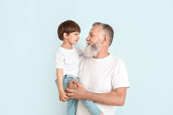 Χαριτωμένο αγοράκι με τον παππού σε ανοιχτόχρωμο φόντο - Φωτογραφία, εικόνα