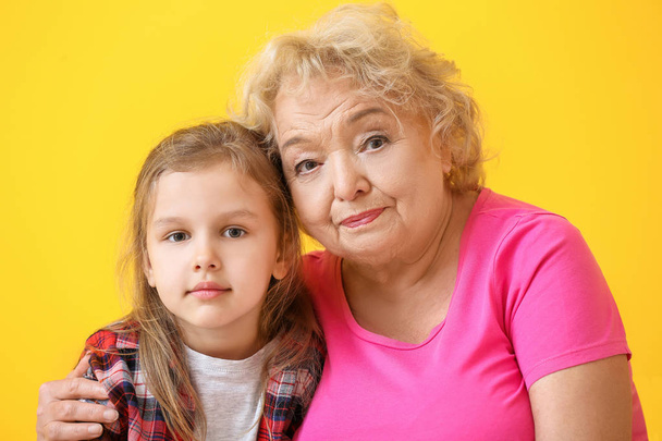 Roztomilá holčička s babičkou na barevném pozadí - Fotografie, Obrázek