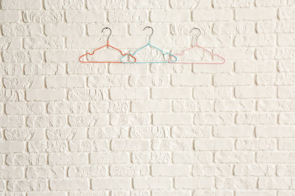 Perchas de ropa en la pared de ladrillo blanco
 - Foto, imagen