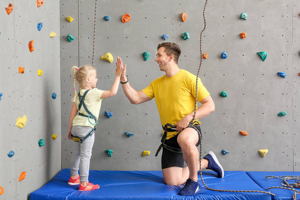 Küçük kız ve eğitmen birbirlerini yüksek-beş spor salonu tırmanma veren - Fotoğraf, Görsel