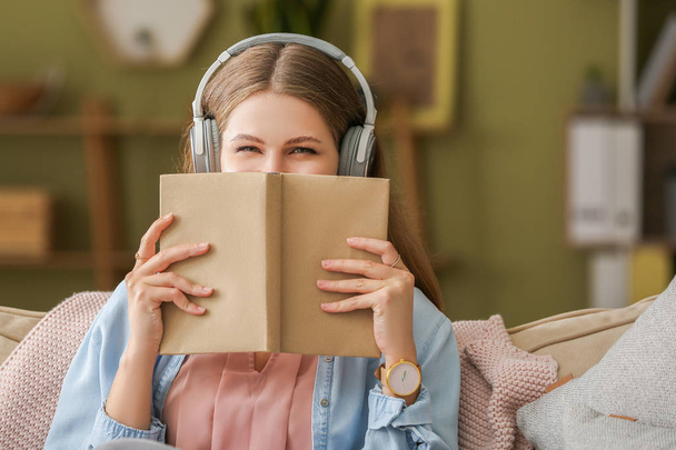 Fiatal nő hallgat hangoskönyv otthon - Fotó, kép
