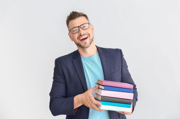 Красивий вчитель чоловічої статі з книгами на світлому фоні
 - Фото, зображення