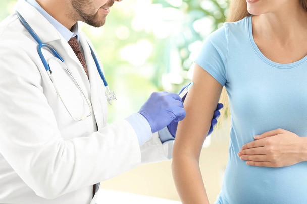 Doctor vaccinating pregnant woman in clinic - Foto, immagini